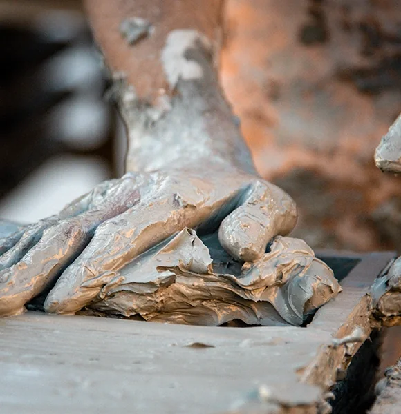 A craftsman's hands working wet clay at a workbench in a Moroccan workshop