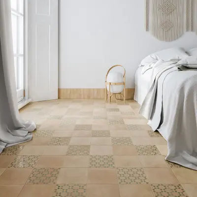 Bedroom floor in sand bejmat scattered with patterned tiles beside a bed and curtain