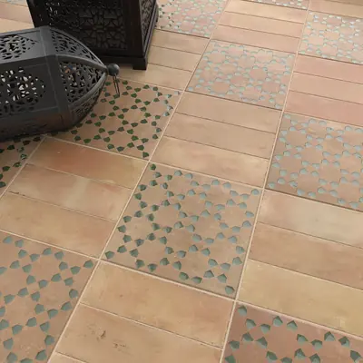 Terracotta bejmat floor with square panels of green patterned tile set into it