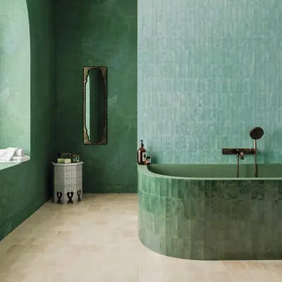 Green glazed bejmat wrapping a bath surround and wall above a sand bejmat floor