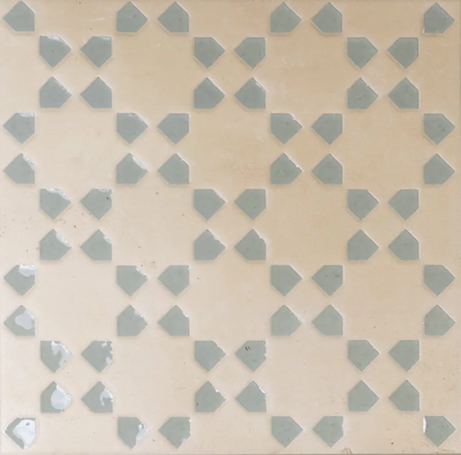 Pale sand bejmat tile with a repeating geometric motif inlaid in green