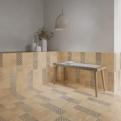 Plastered room with a sand bejmat floor edged by a border of patterned tiles