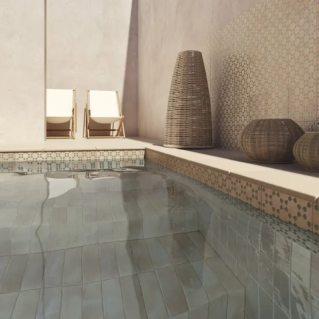 A pool surround in pale bejmat with a patterned tile border running along the water's edge