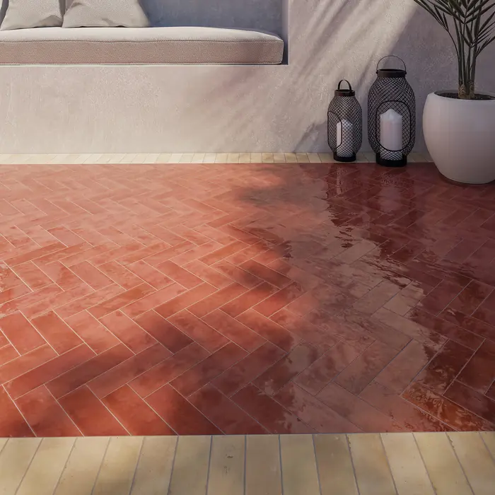 Glazed red bejmat laid in a tight herringbone across a floor beside metal lanterns
