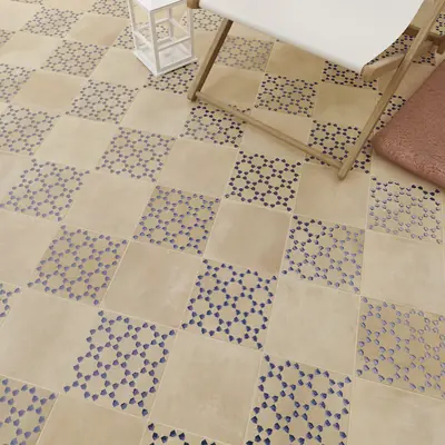 Sand bejmat floor with blue patterned tiles set through it beside a folding deck chair