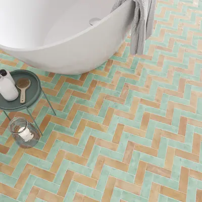 Turquoise and terracotta bejmat laid in herringbone beneath a freestanding bath