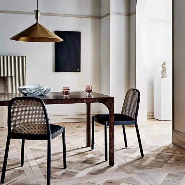 A spun brass cone pendant light hanging low over a dark wood dining table