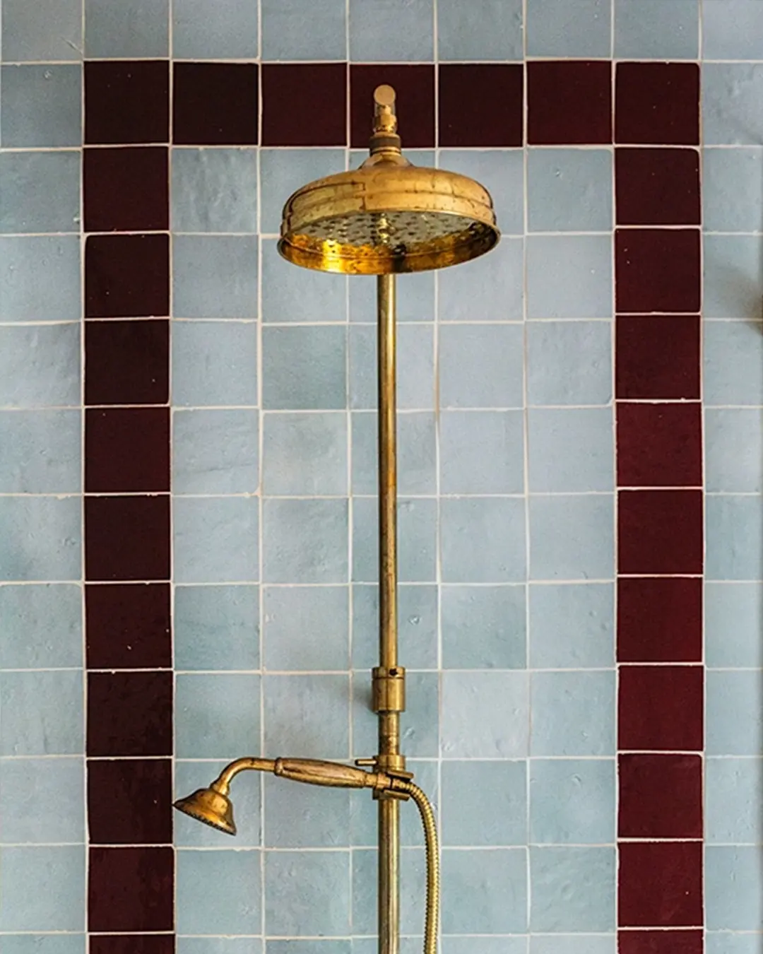 Pale blue zellige shower wall with a deep red zellige border framing the shower set