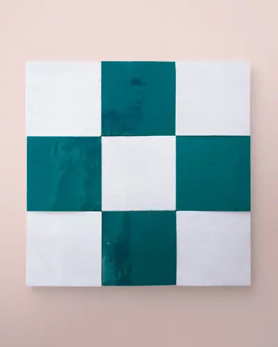 Teal and white zellige tiles set as a checked panel on a pale pink wall