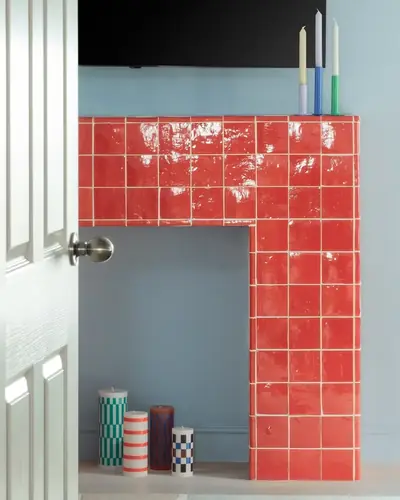 Coral red zellige tiles forming a rectangular fireplace surround against a white wall