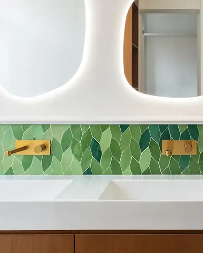 Green and white petal-shaped zellige mosaic running behind two wall-hung basins