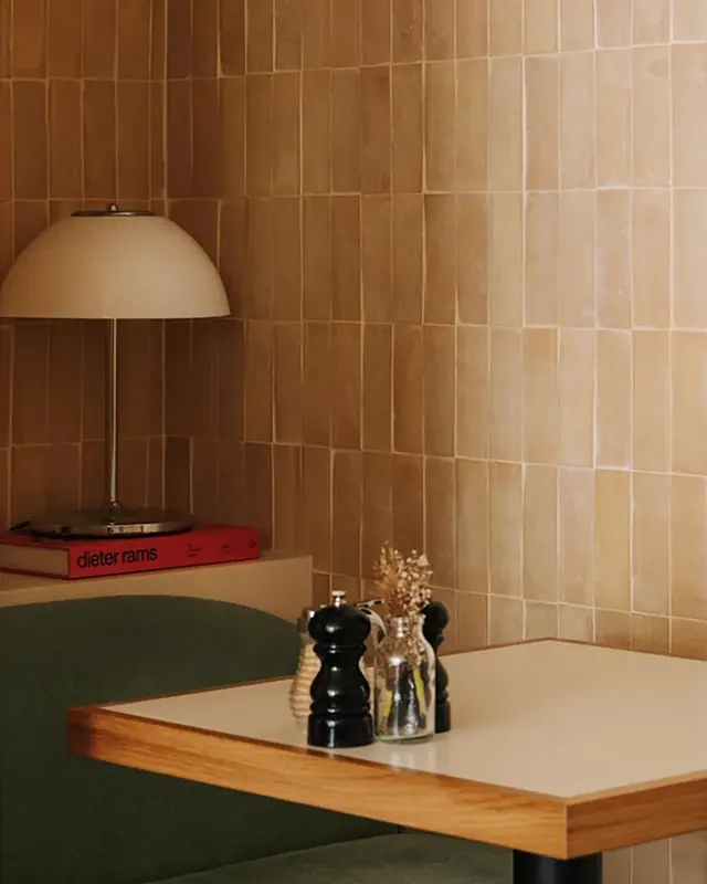 Warm clay-toned zellige lining the wall above a restaurant banquette