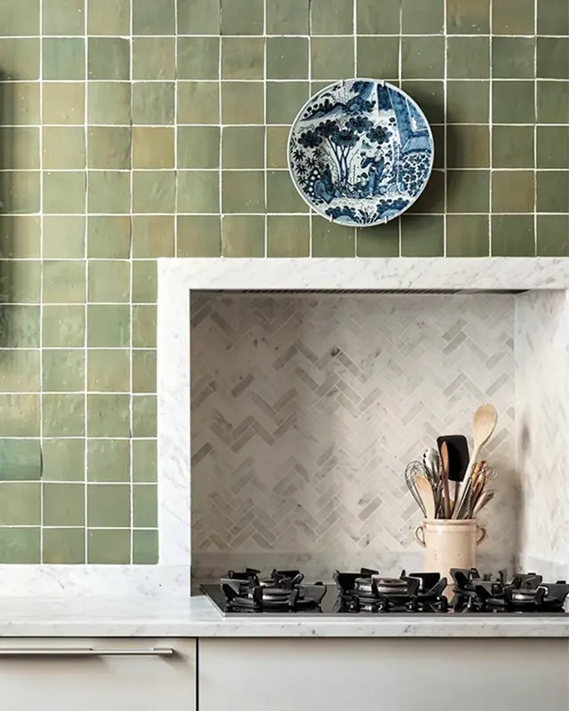 Pale sage green zellige wall framing a marble-lined cooking niche