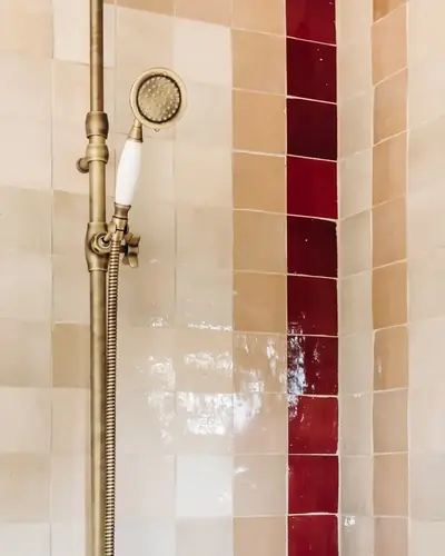 Shower walls in beige, pink and deep red zellige laid as vertical bands