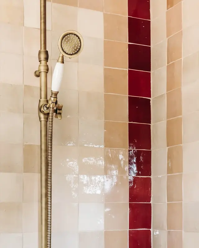 Shower walls in beige, pink and deep red zellige laid as vertical bands