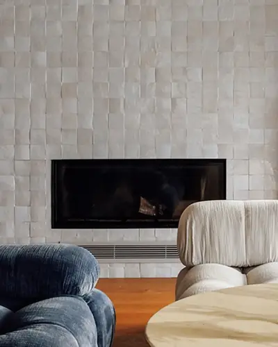 White zellige tiles surrounding a linear fireplace in a pale living room